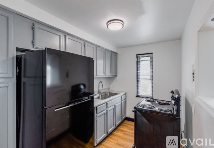 A kitchen with a black refrigerator and wooden floors.