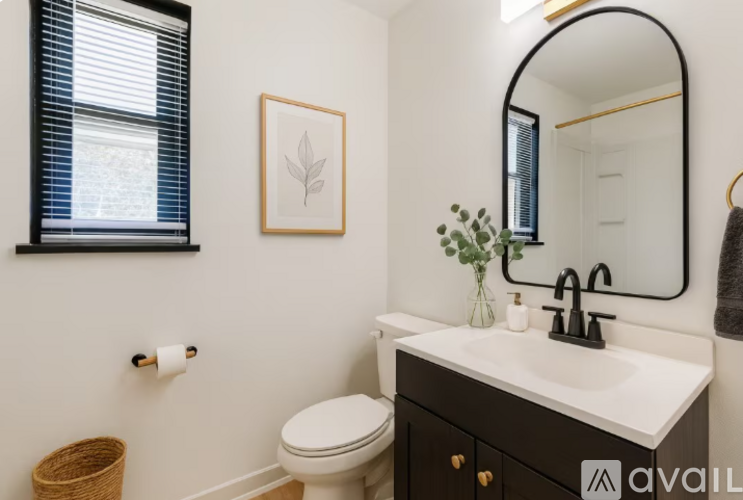 A bathroom with a toilet, sink, mirror, and a plant.