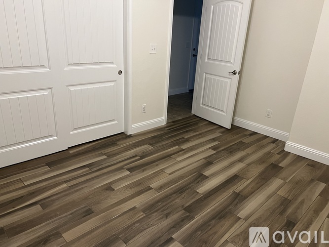 A room with white doors and wooden flooring.