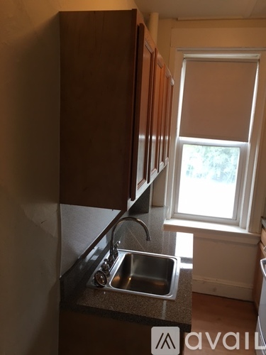 A kitchen with brown cabinets and a window.