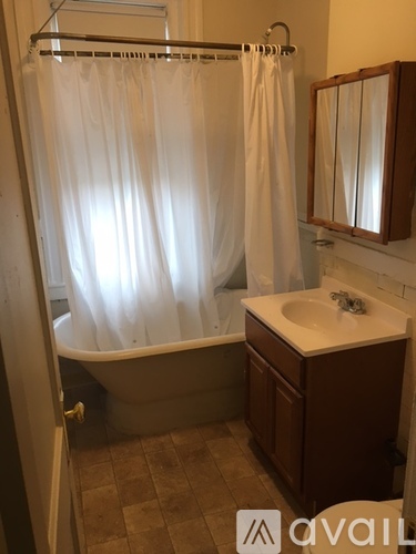 A bathroom with a white shower curtain and brown cabinetry.