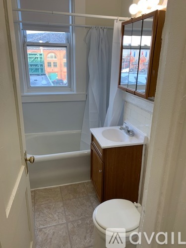 A bathroom with a toilet, sink, and a window.
