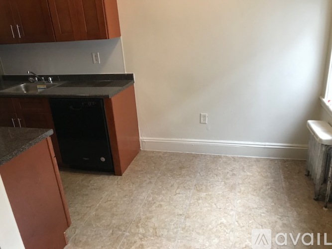 A kitchen area with brown cabinets and a black dishwasher.