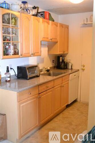 A kitchen with wooden cabinets and a counter top with a toaster and a bottle on it.
