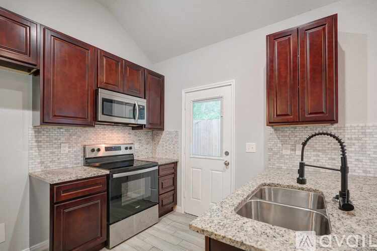 A kitchen with a sink, stove, and microwave.