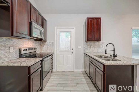 A kitchen with dark wood cabinets and a white door.