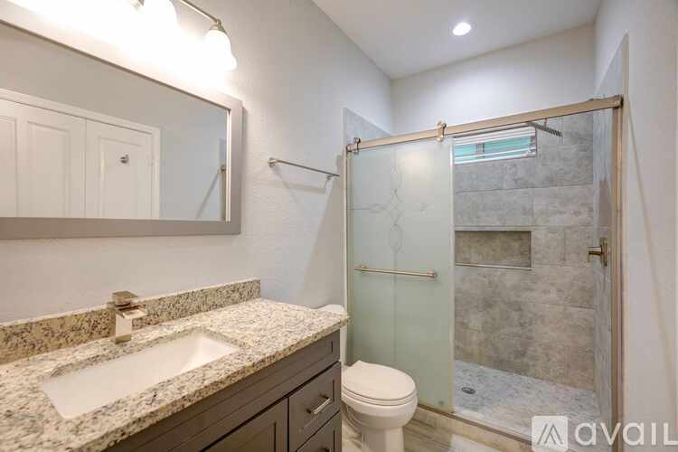 A bathroom with a marble countertop and a walk-in shower.