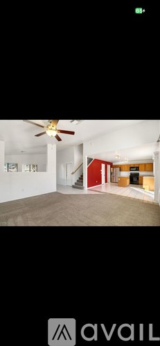 A room with a ceiling fan and a red wall.