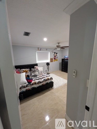 A bedroom with a bed, dresser, and ceiling fan.