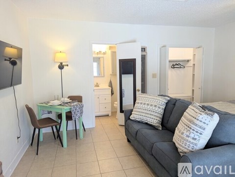 A living room with a grey couch and a dining table with chairs.