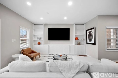 A modern living room with a white couch and a flat screen TV mounted on the wall.