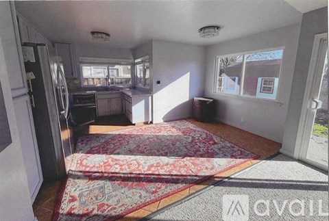 A kitchen with a rug on the floor and a fridge on the left.
