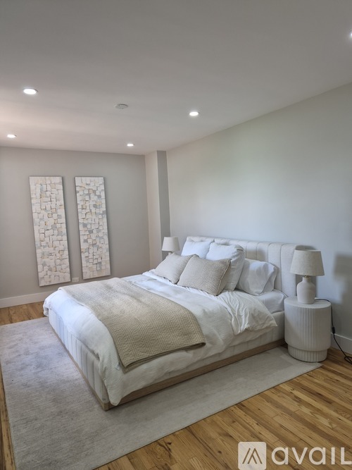 A bedroom with a large bed and two wall art pieces.