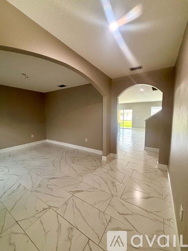 A spacious room with marble flooring and a large arched doorway.