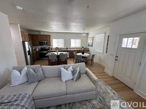 A living room with a grey couch and a kitchen in the background.