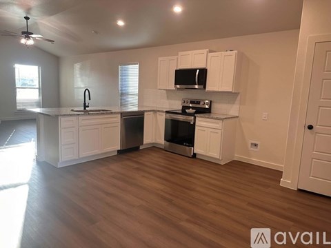 A kitchen with white cabinets and a wooden floor.