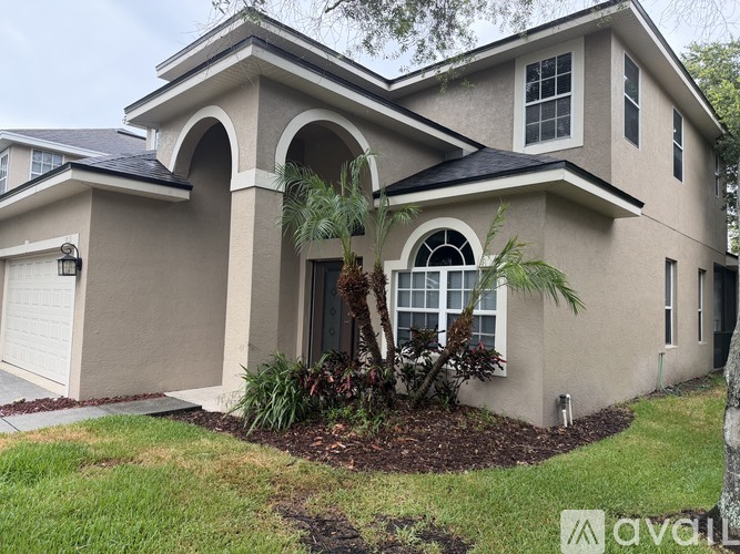A beige house with a black roof and a white garage door.
