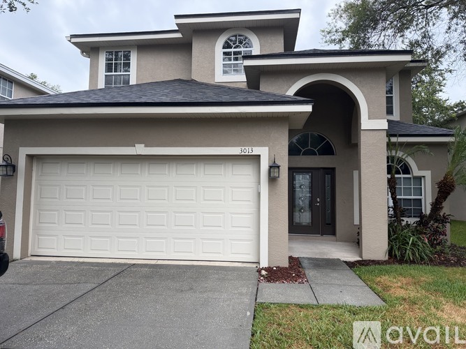A two-story house with a white garage door and a black roof.