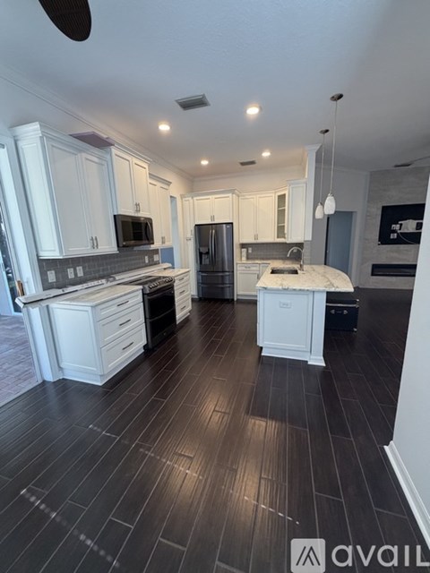 A modern kitchen with white cabinets and black flooring.