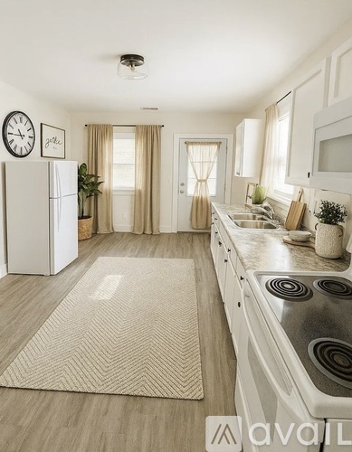 A kitchen with a white fridge, stove, and cabinets with a rug on the floor.