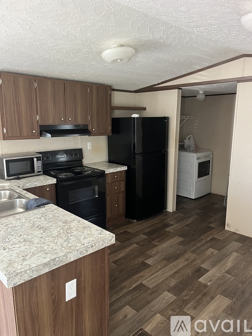 A kitchen with wooden cabinets and a black refrigerator.