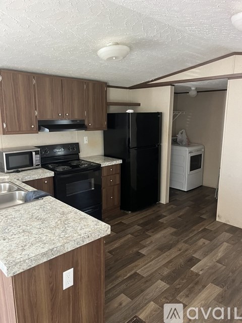A kitchen with wooden cabinets and a black refrigerator.