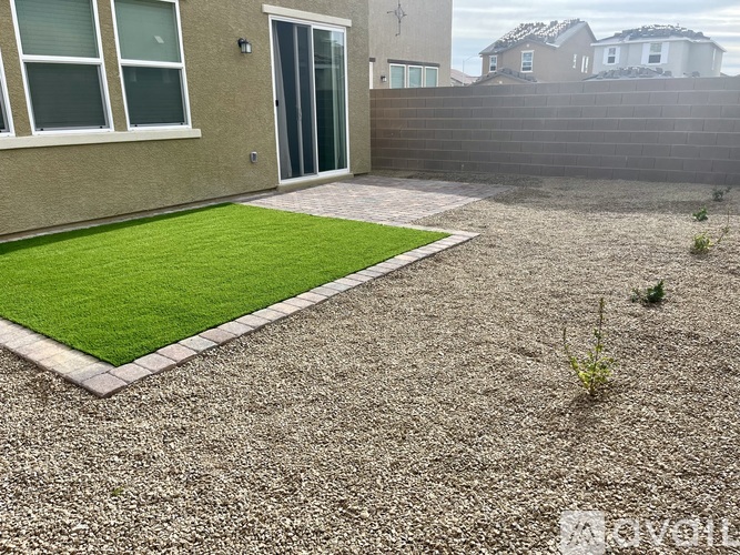 A backyard with a gravel area and a small grassy section.