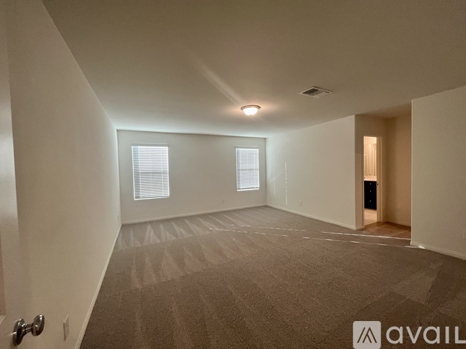 A spacious room with carpeted floor and two windows.