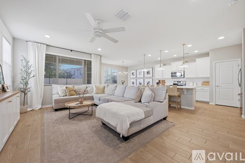 A spacious living room with a white sofa set and a wooden floor.