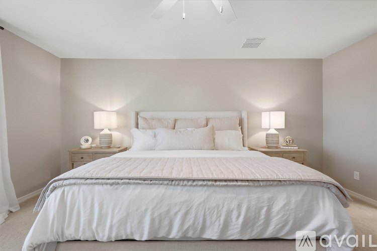 A bedroom with a large bed and two nightstands with lamps.