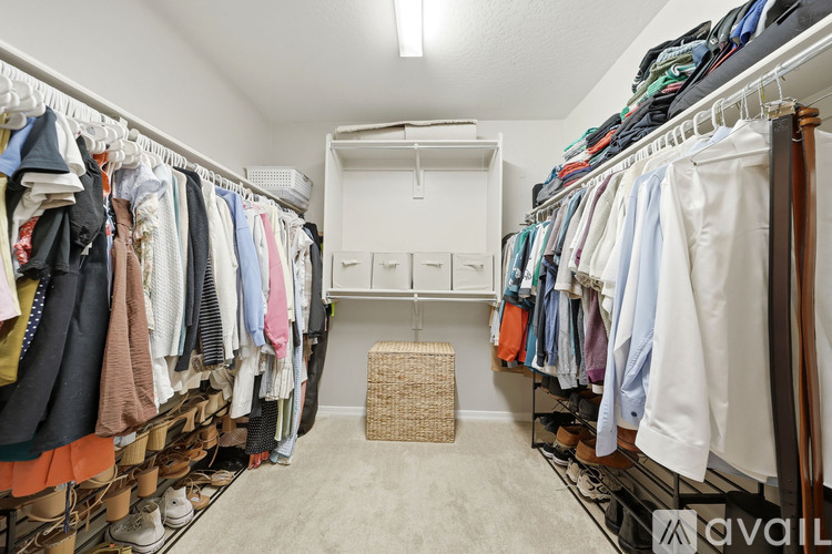 A spacious walk-in closet with clothes and shoes on shelves.
