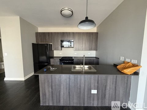 A kitchen with a black fridge and a black countertop.