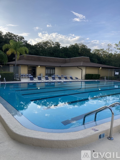 A swimming pool with lounge chairs and a building in the background.