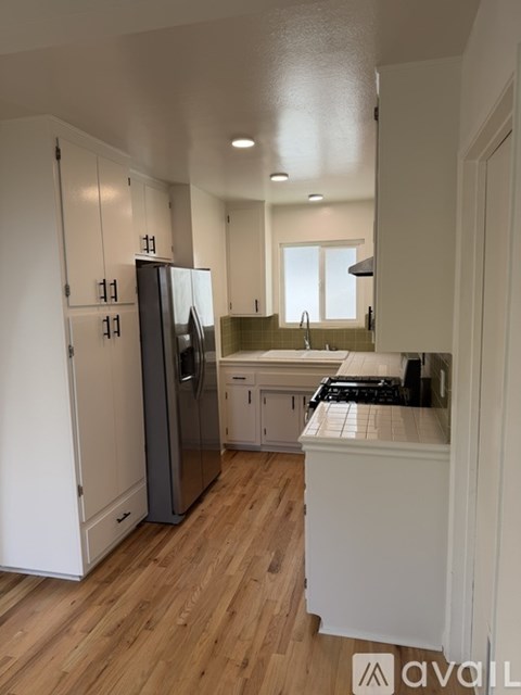 A kitchen with white cabinets and a stainless steel refrigerator.
