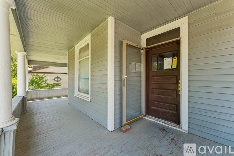A porch with a brown door and a window.