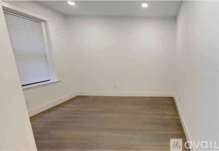 A room with wooden flooring and a window with blinds.