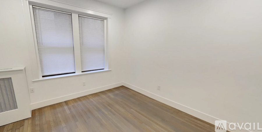 A room with wooden flooring and a window with blinds.