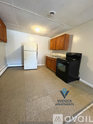 A kitchen area with a white fridge, black stove and wooden cabinets.
