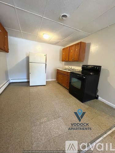 A kitchen area with a white fridge, black stove and wooden cabinets.