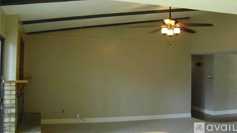 A room with a ceiling fan and a wall socket.