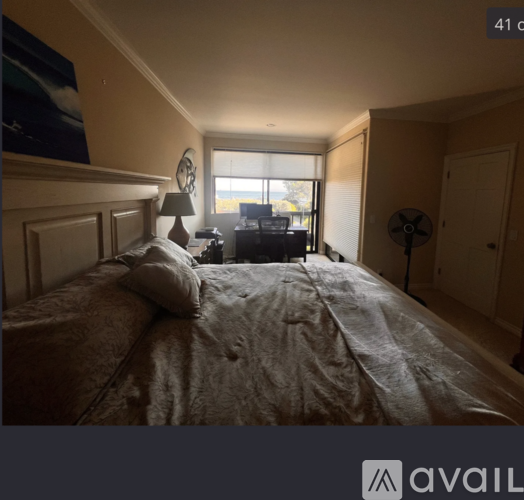 A bedroom with a large bed and a window overlooking the ocean.