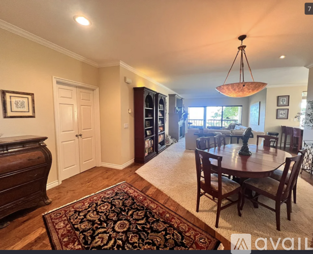 A living room with a rug, a dining table and chairs, and a cabinet.