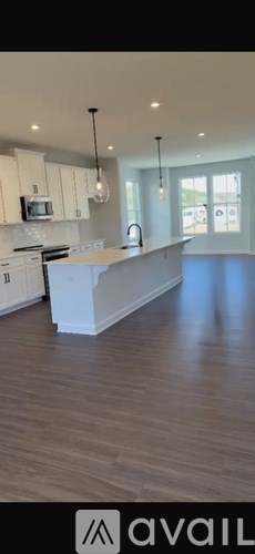 A modern kitchen with white cabinets and a wooden floor.