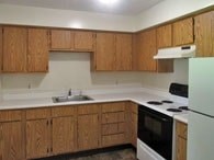A kitchen with wooden cabinets and white appliances.