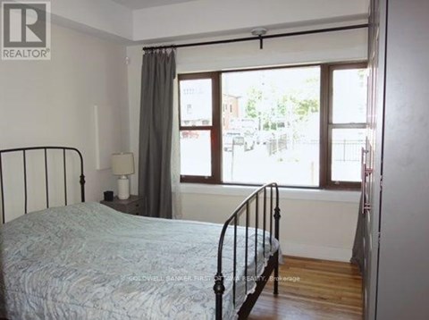 A bedroom with a bed, nightstand, and window.