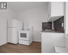 A kitchen with white appliances and a wooden floor.
