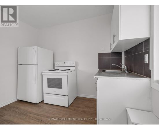 A kitchen with white appliances and a wooden floor.