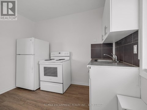 A kitchen with white appliances and a wooden floor.