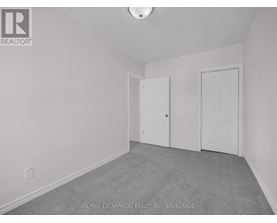 A room with a carpeted floor and two doors.