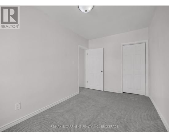 A room with a carpeted floor and two doors.